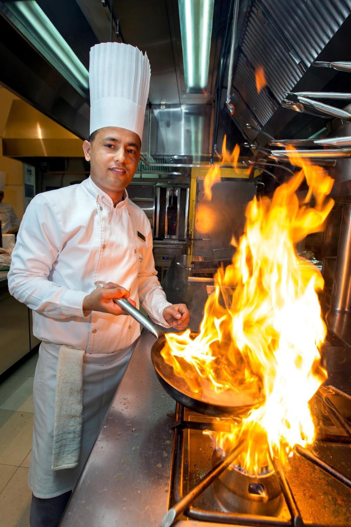 라 시갈 호텔 매니지드 바이 아코르 도하 외부 사진 A chef cooking with a flaming skillet